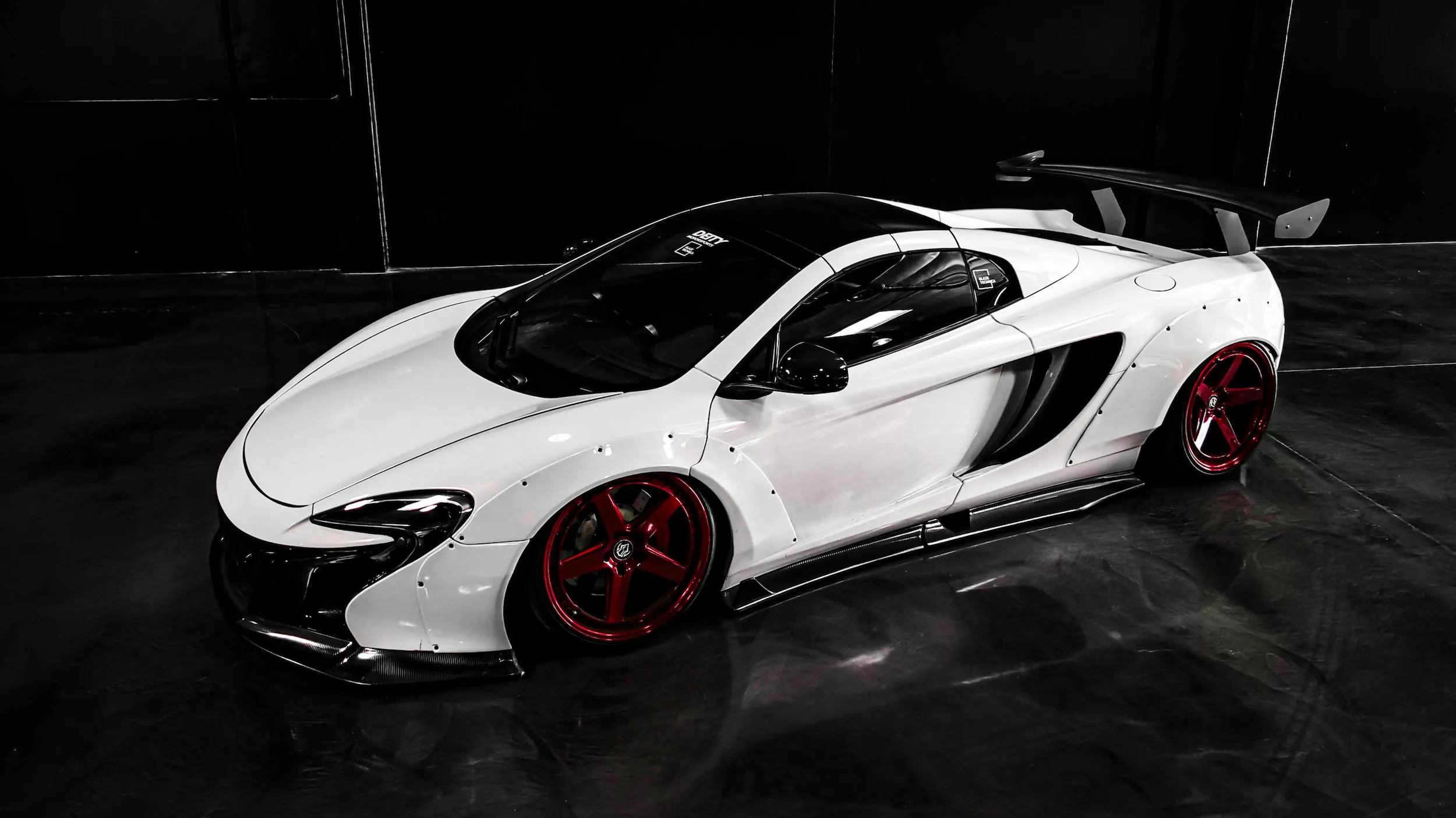 Custom wide body white McLaren 650S supercar with red alloy wheels and carbon fibre splitter, professionally detailed and paint protected